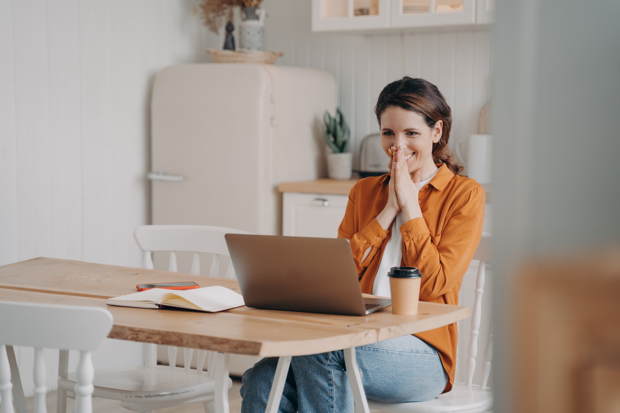 Surprised excited young woman is sitting in front of laptop having video call