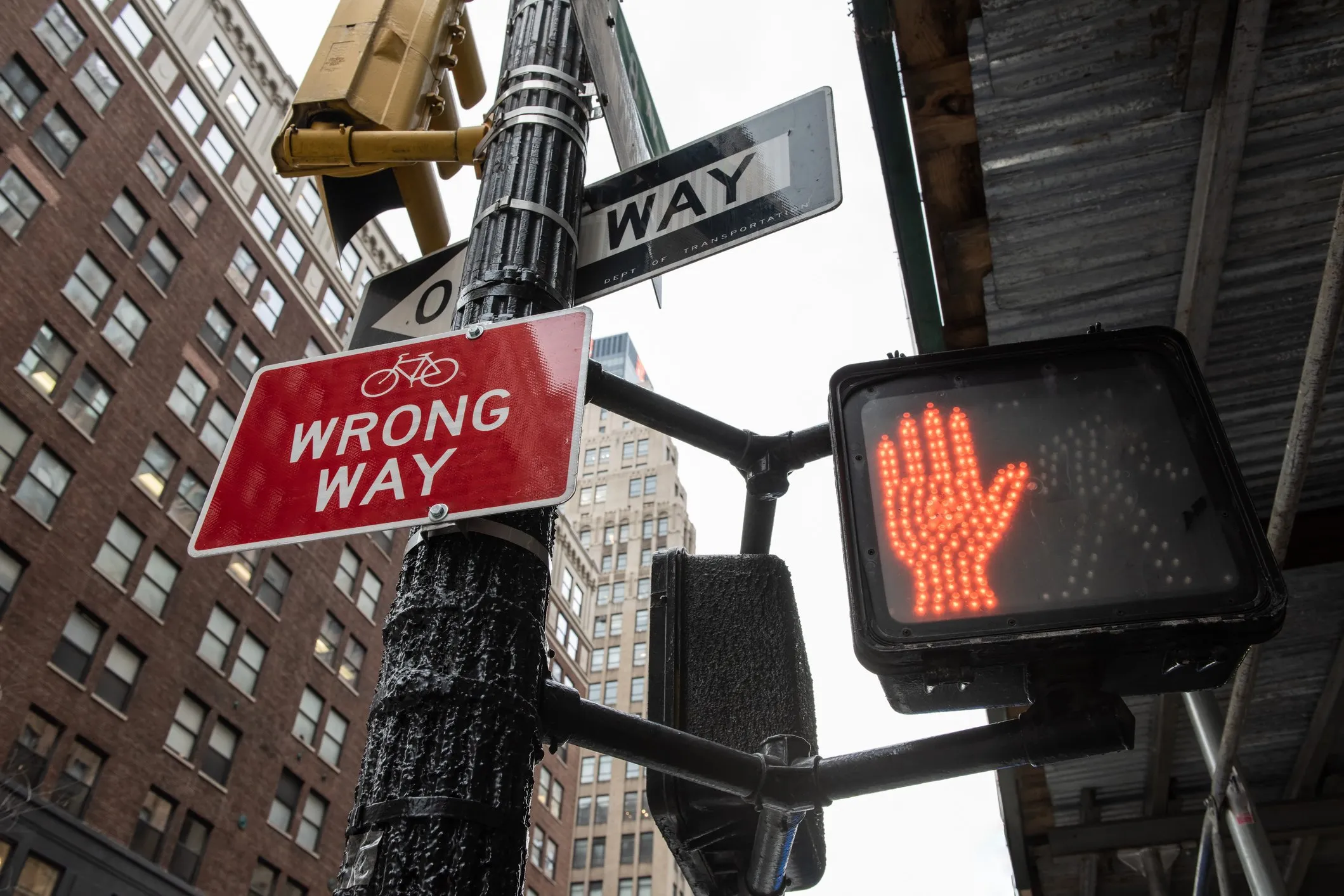 Corner of a city street featuring caution signs, including a Red Hand to stop, a red sign, and a One-Way sign, symbolizing the dangers and misleading directions often associated with debt relief scams