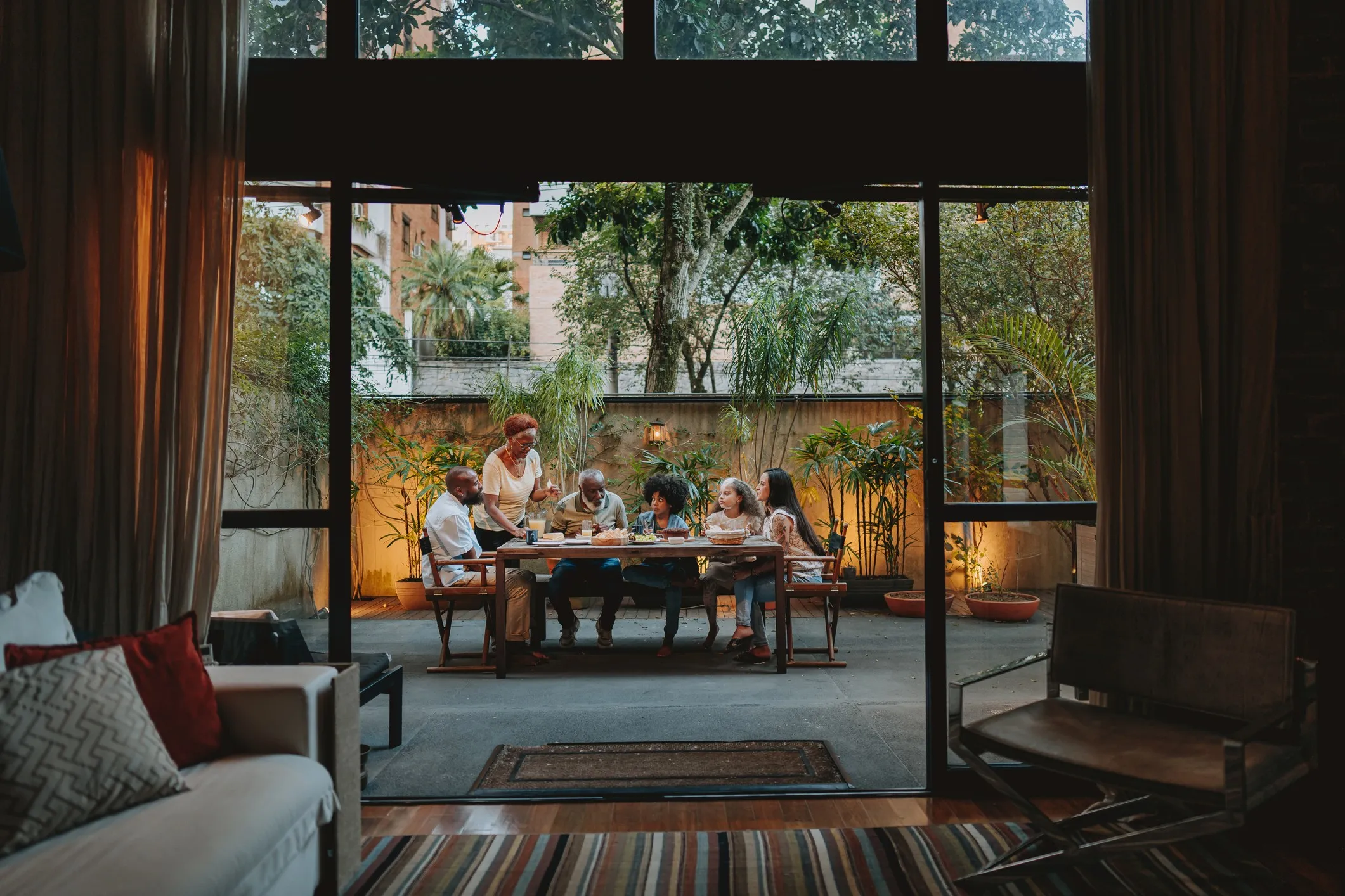 Family gathered around the large wooden dining table in the outside dining room of their home